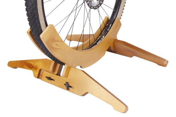 Велосипедное колесо в деревянной подставке для велосипеда. Ширина подставки отрегулирована по ширине колеса. Ширина зафиксирована барашками.